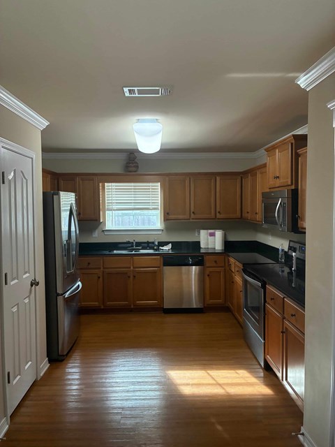A kitchen with wooden cabinets and a stainless steel refrigerator.