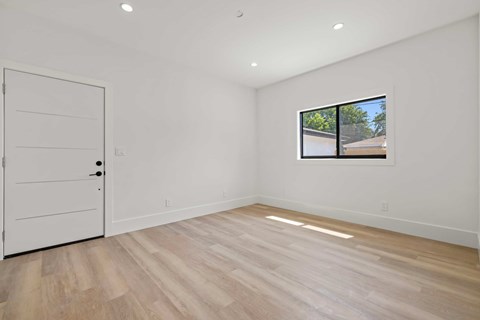 A room with a white door and a window with a view of a building outside.