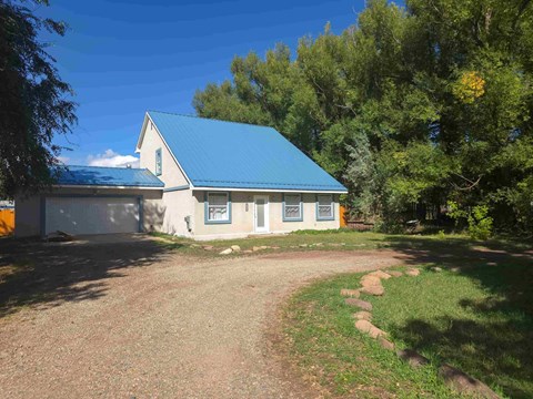 A small house with a blue roof is surrounded by trees.