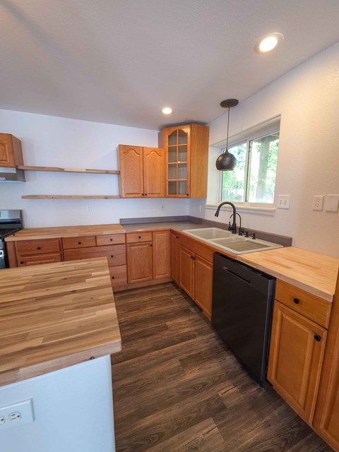 A kitchen with wooden cabinets and a black dishwasher.