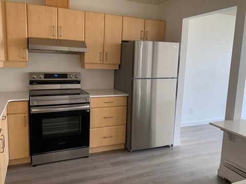 A kitchen with wooden cabinets and a stainless steel refrigerator.