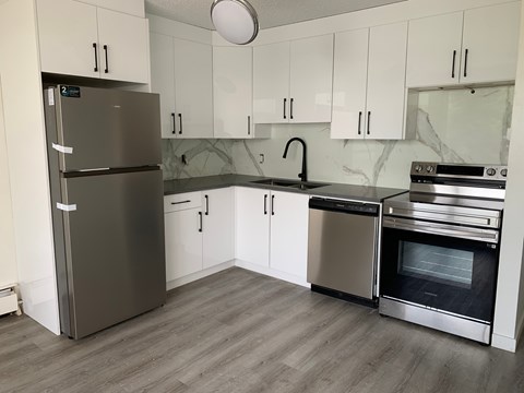 A kitchen with a refrigerator, oven, and sink.
