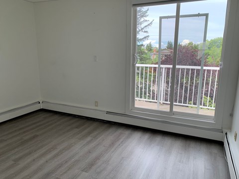A room with a large window and a wooden floor.