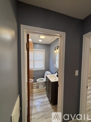 A bathroom with a toilet, sink, and window.