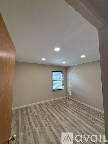 A room with wooden flooring and a window with blinds.