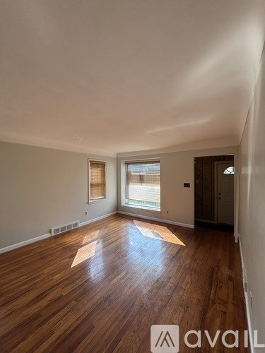 A room with wooden floors and a window with blinds.