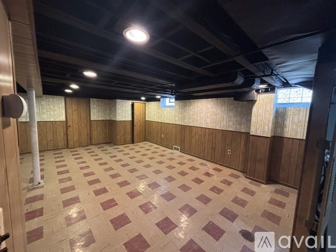 A large empty room with a checkered floor and wooden walls.