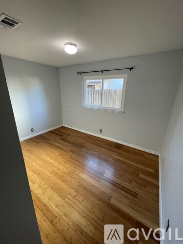 A room with wooden flooring and a window with blinds.