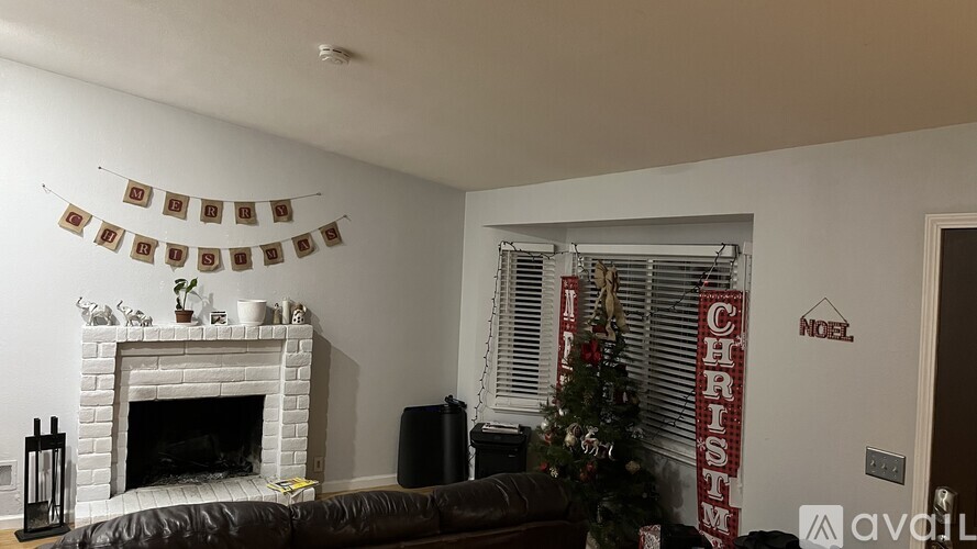 A living room with a fireplace, a Christmas tree, and a sign that says "NOEL CHRISTMAS".