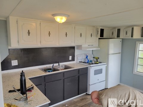 A kitchen with white cabinets and a black counter top.