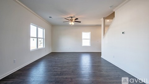 A spacious room with a ceiling fan and wooden flooring.