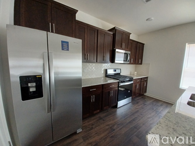 A kitchen with a stainless steel refrigerator and wooden cabinets.