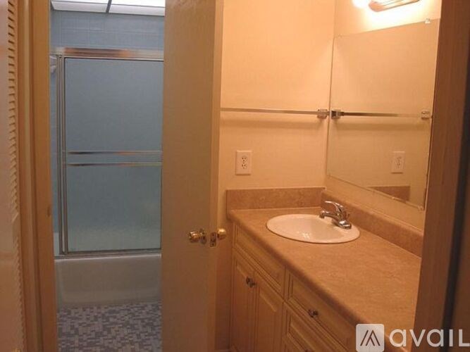 A bathroom with a sink, mirror, and a glass door.