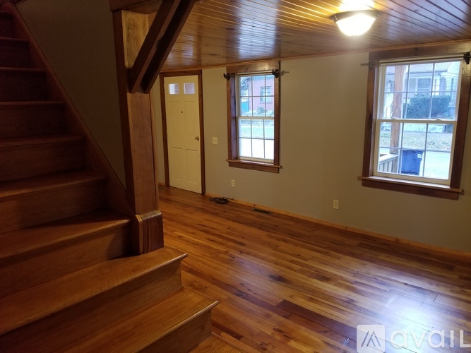 A room with wooden floors and a staircase leading to the upper floor.