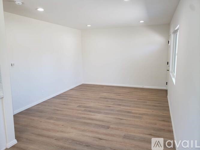 A room with wooden flooring and white walls.