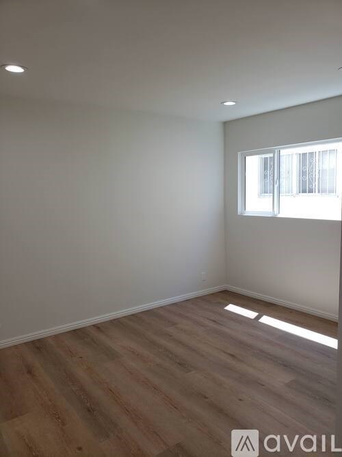 A room with wooden flooring and a window letting in sunlight.
