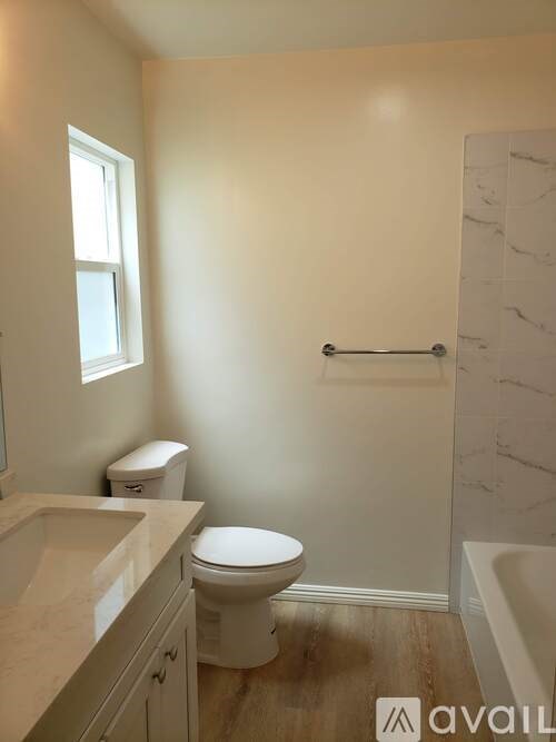 A bathroom with a toilet, sink, and a window.