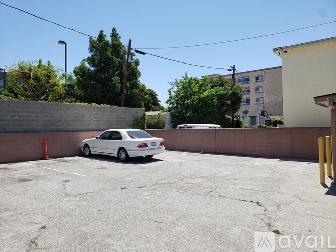 A white car is parked in a concrete lot.