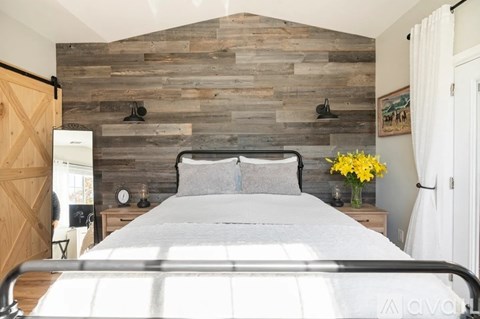 A bedroom with a bed, nightstands, and a wooden wall.