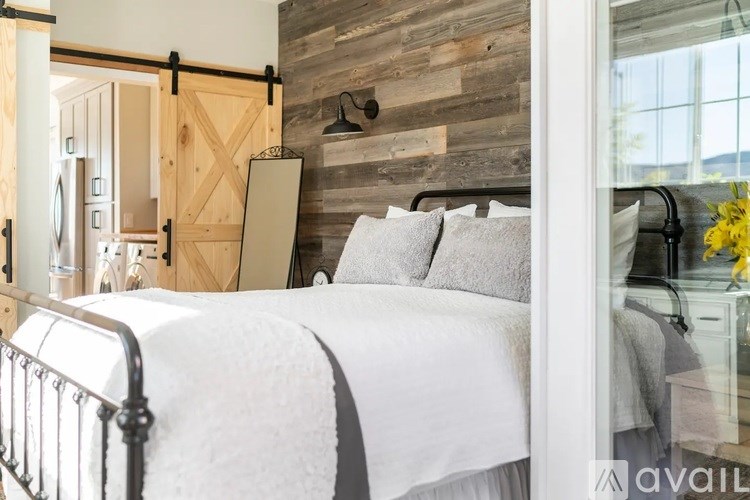 A bedroom with a white bed and a wooden wall.