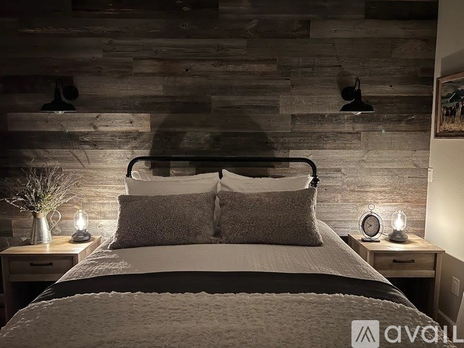 A bedroom with a bed, nightstands, and a wooden wall.