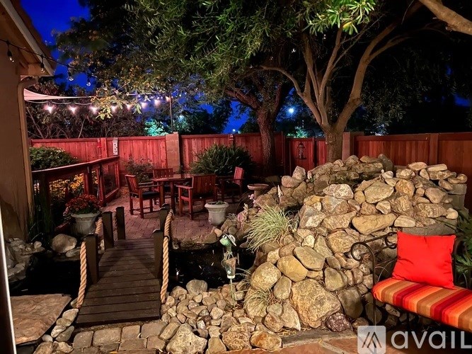 A backyard with a stone wall and a wooden deck.