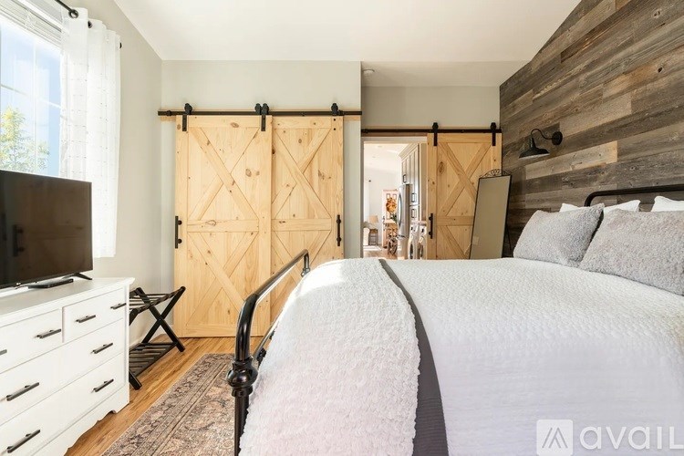 A bedroom with a bed, a TV, and a wooden wall.
