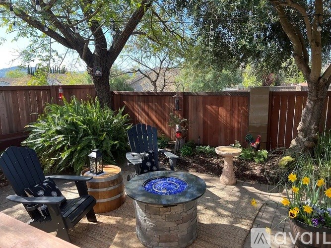 A backyard with a fire pit and chairs.