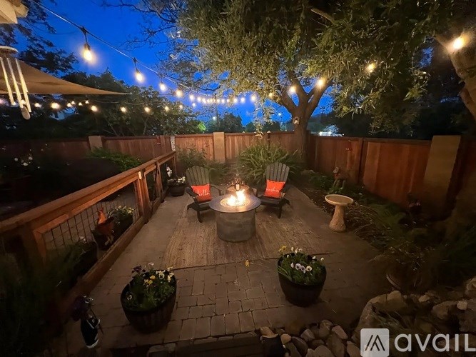 A backyard patio with a fire pit and chairs.