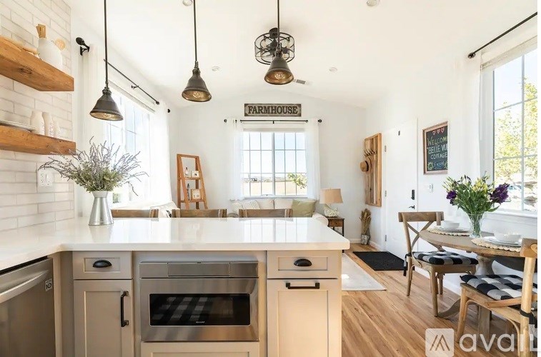 A kitchen with a white brick wall and wooden floors.