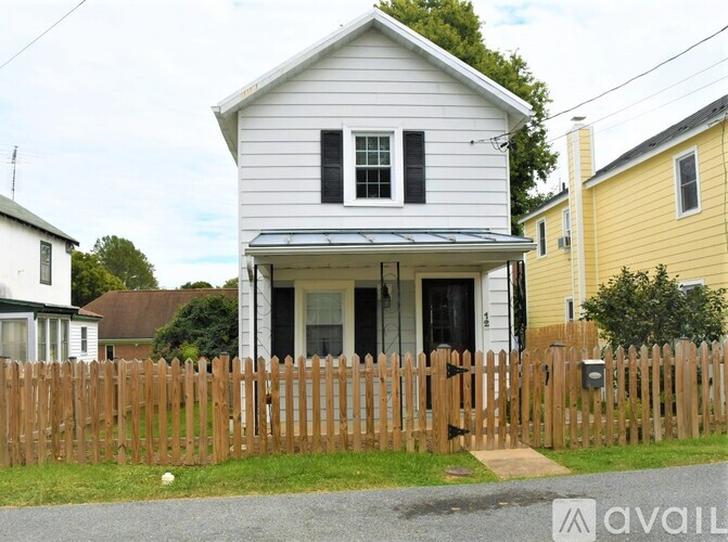 A white house with a wooden fence in front of it.