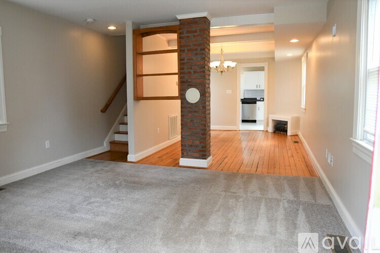 A living room with a grey carpet and a brick pillar.