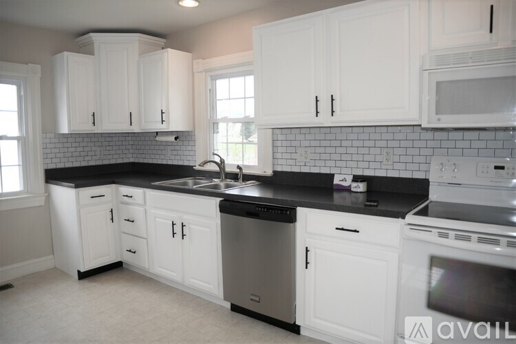 A kitchen with white cabinets and black countertops.