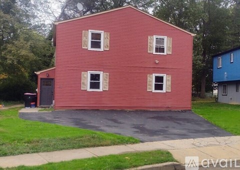 A red house with a car parked in front.