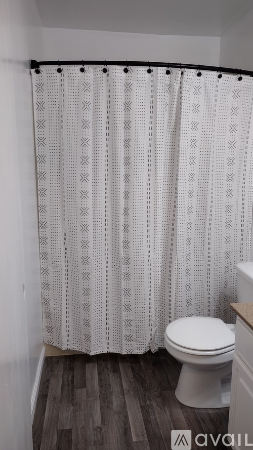 A bathroom with a toilet and a shower curtain with a pattern.