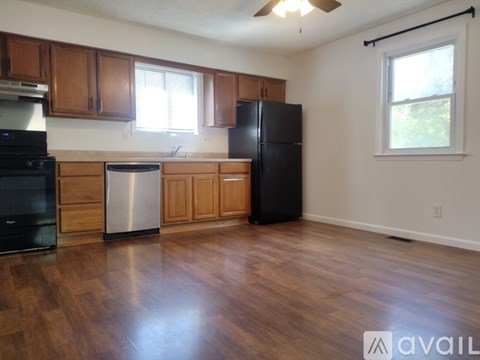 A kitchen with wooden cabinets and a black refrigerator.