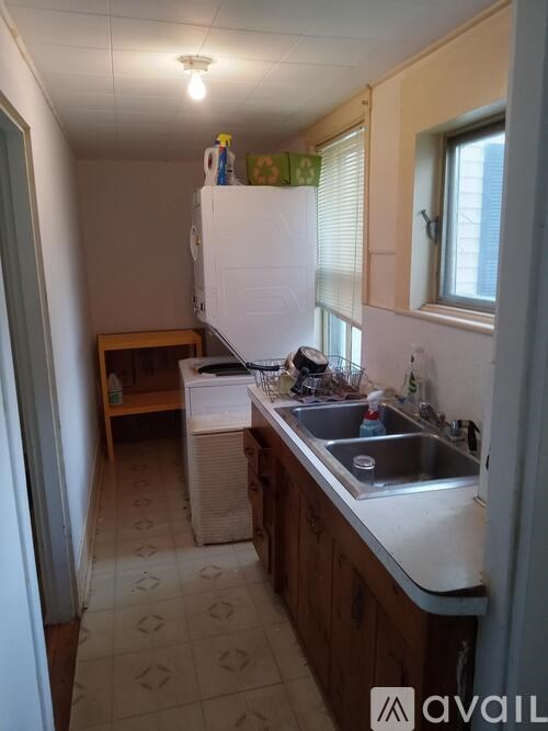 A kitchen with a white fridge, wooden cabinets, and a tiled floor.