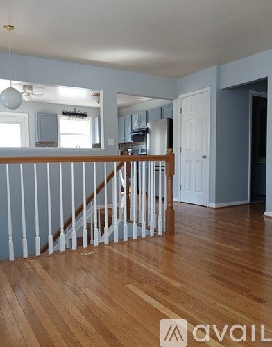 A room with wooden floors and a staircase with white railings.