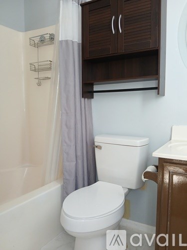 A white toilet sits next to a white bathtub in a bathroom.