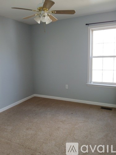 A room with a ceiling fan and a window.