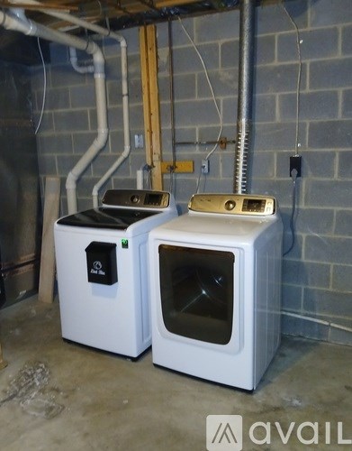Two white ovens in a basement.