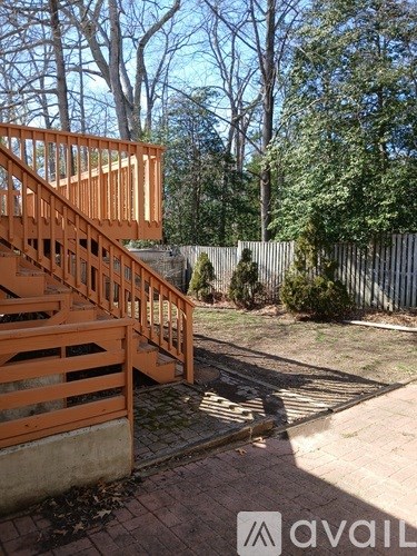 A wooden staircase with a railing leads up to a backyard with a fence.