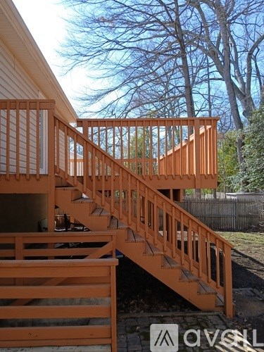 A wooden staircase with a railing is in front of a house.