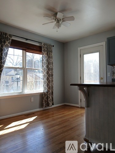 A room with a ceiling fan and a window with curtains.
