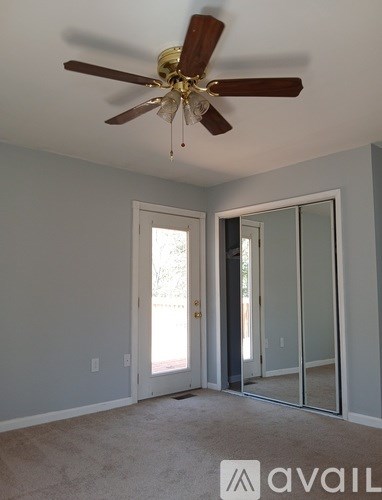 A room with a ceiling fan and sliding glass doors.