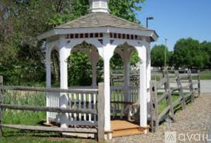 A gazebo with a white railing and a brown roof is surrounded by a wooden fence.