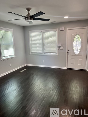 A room with a ceiling fan and wooden flooring.