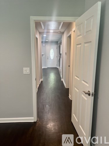 A hallway with white doors and a light switch on the wall.