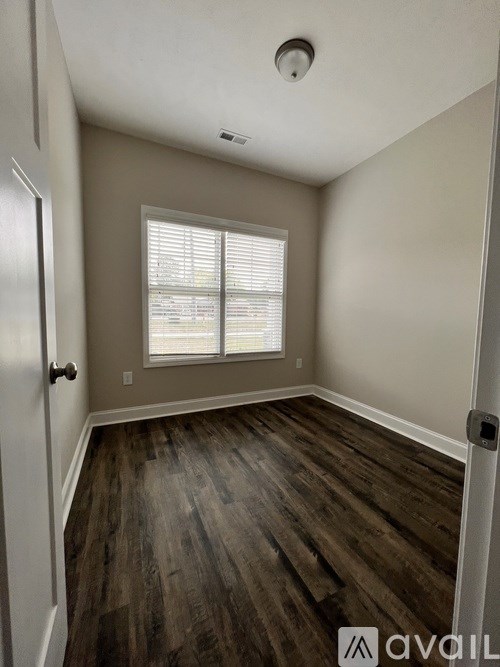 A room with wooden flooring and a window with blinds.