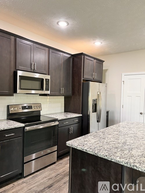 A kitchen with dark brown cabinets and granite countertops.